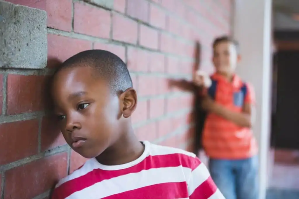 choolkid bullying a sad boy in corridor at school